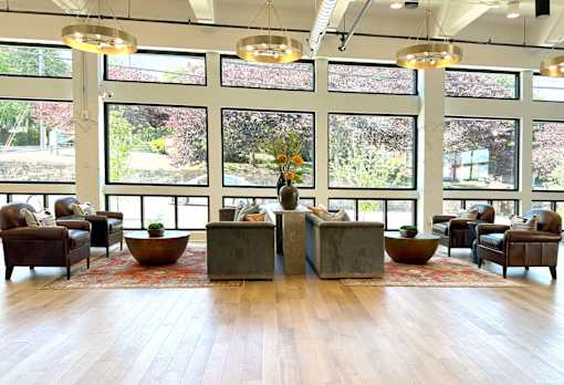 A large room with wooden floors and a long table with a vase of flowers on it.