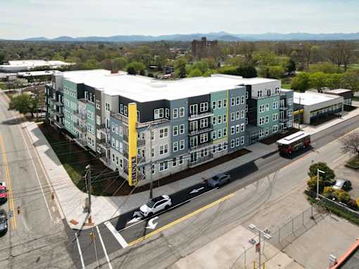 A large apartment complex is situated on a street corner with a view of the mountains in the distance.