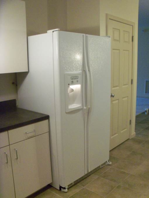 A white refrigerator with a water and ice dispenser in the middle of the door.