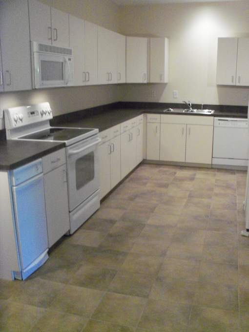 A kitchen with white cabinets and a black counter top.