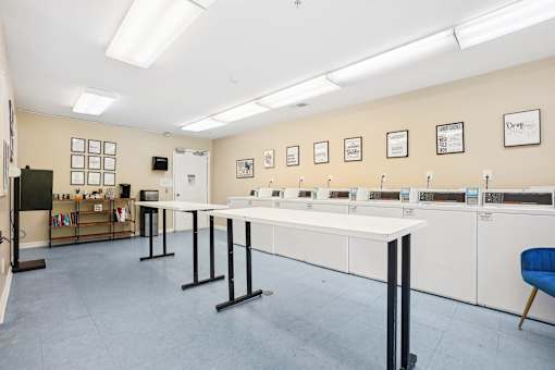 A room with tables and chairs and a whiteboard on the wall.