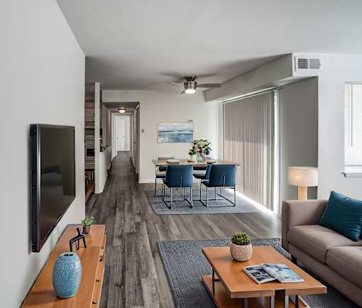 A modern living room with a wooden floor and a flat screen TV mounted on the wall.