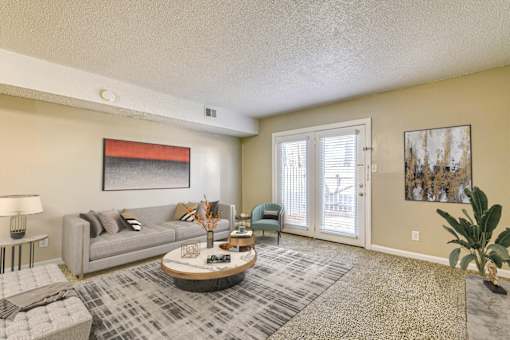 A living room with a grey couch, a coffee table, and a painting on the wall.
