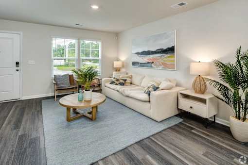 A living room with a white couch, a wooden coffee table, and a painting on the wall.
