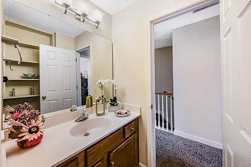 A bathroom with a sink, mirror, and a vase of flowers.