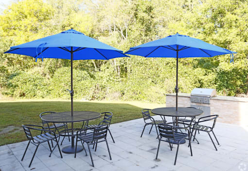 A patio with a table and chairs under blue umbrellas.