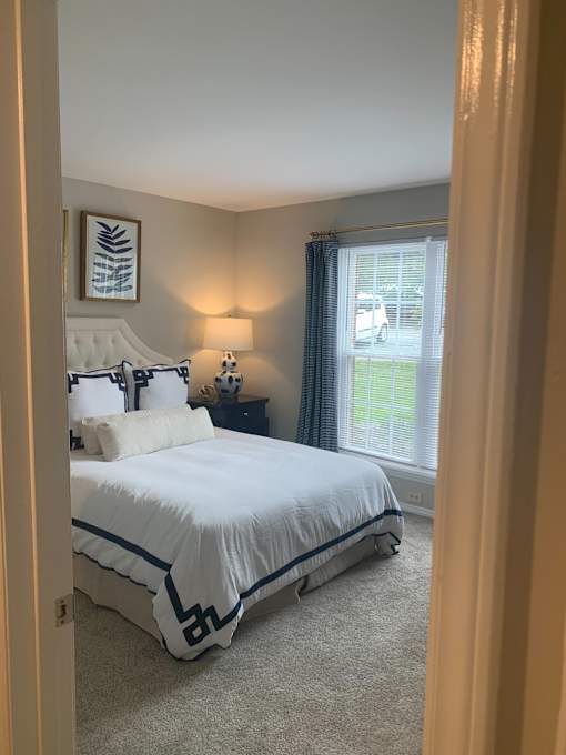 A bedroom with a large bed and a window with a view of a parking lot.