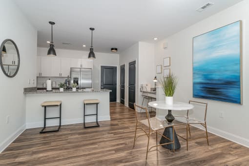 a dining area with a table and chairs and a kitchen in the background