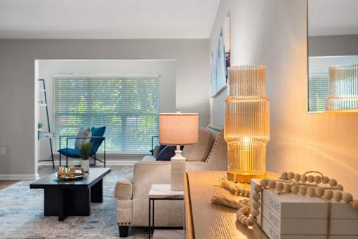 A modern living room with a large window, a sofa, a coffee table, and a lamp.