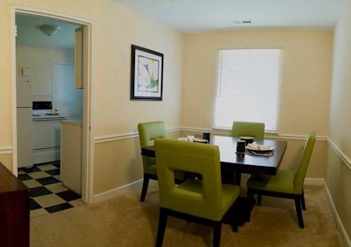 View of dining room model with square table and four green chairs