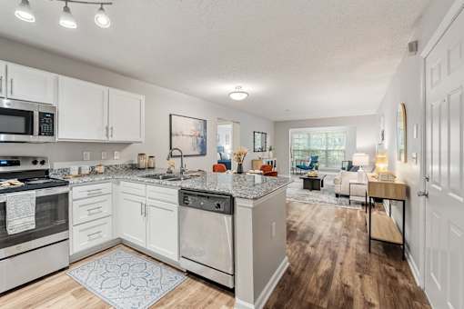 A kitchen with white cabinets and a patterned rug on the floor.