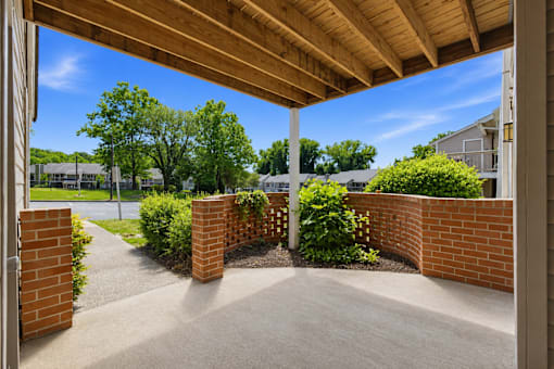 A patio with a wooden roof and brick pillars.