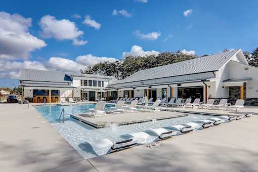 A large swimming pool with lounge chairs and a building in the background.