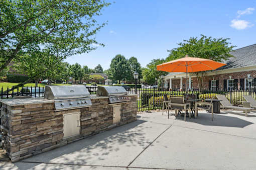 A picnic area with a stone wall and a grill.