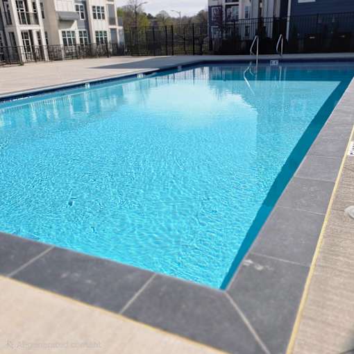 A large blue swimming pool with a black fence around it.
