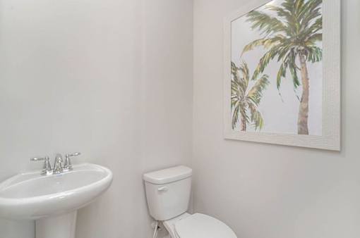 A white toilet sits next to a white sink in a bathroom.