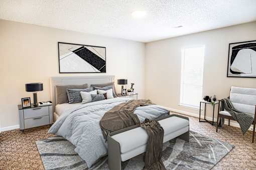 A bedroom with a large bed and a chair.