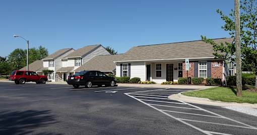 A black car is parked in a parking lot in front of a building.