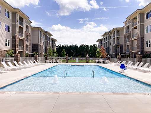 A large swimming pool in front of apartment buildings.