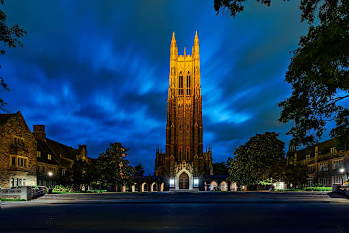 A tall tower stands in the center of a courtyard surrounded by buildings.