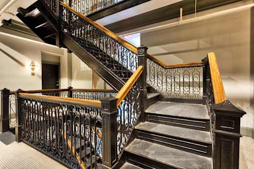 A staircase with a black metal railing and wooden steps.