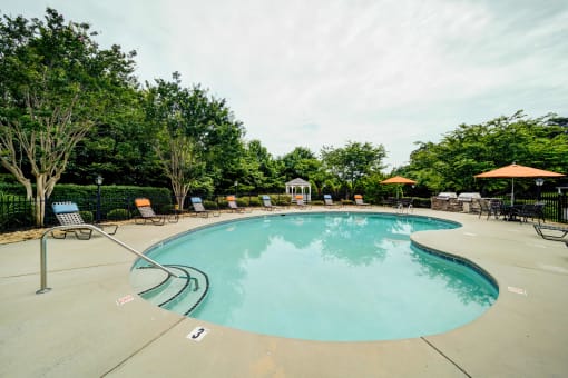 Resort Style Kidney Shaped Pool with Lounge Chairs and Tables with Umbrellas Around