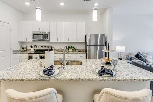 A modern kitchen with a granite countertop and white cabinets.