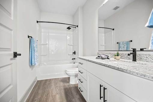 A bathroom with a white toilet, a sink, and a mirror.