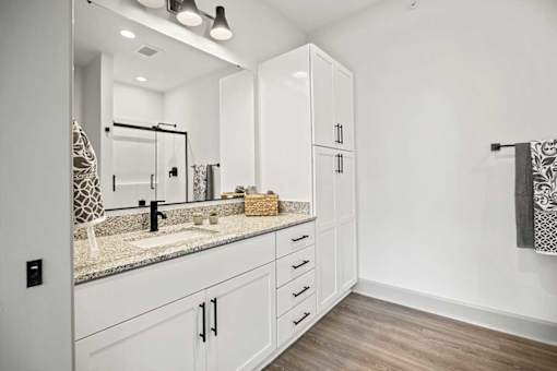 A bathroom with a sink, mirror, and cabinets.