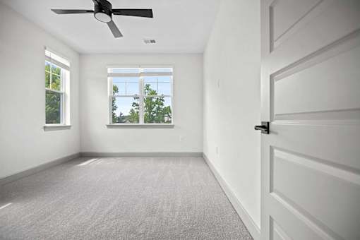 A room with a ceiling fan and a door.