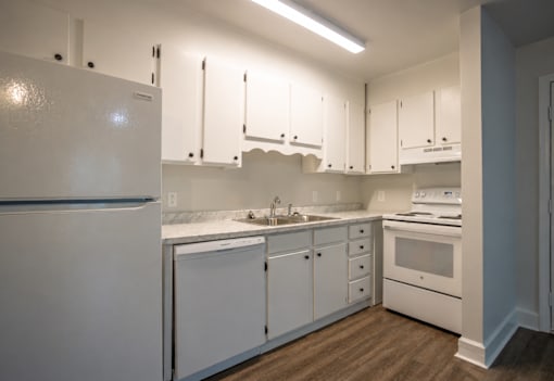 A white kitchen with a refrigerator, sink, and oven.