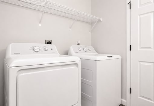 Two white front loading washing machines in a laundry room.