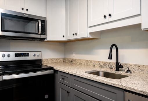 A modern kitchen with a black stove and a granite countertop.