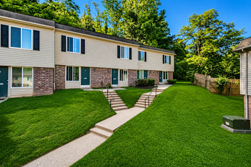 A grassy area in front of a building with a concrete pathway.