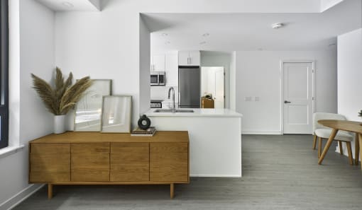 a kitchen and living room with white walls and a wooden dresser