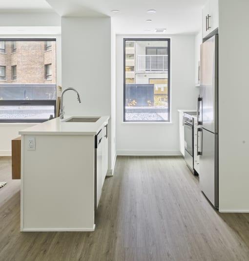 an empty kitchen with a large window and a sink and a refrigerator