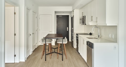 a kitchen with white cabinets and a wooden table and chairs