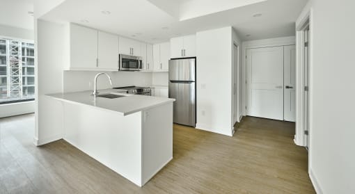 an empty kitchen with white cabinets and a stainless steel refrigerator