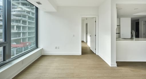 a hallway with white walls and wood floors and a large window
