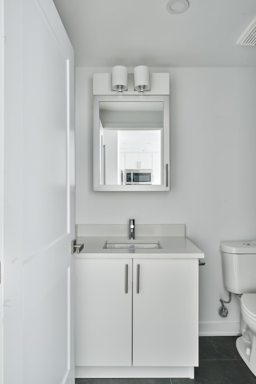 a white bathroom with a sink and mirror and a toilet
