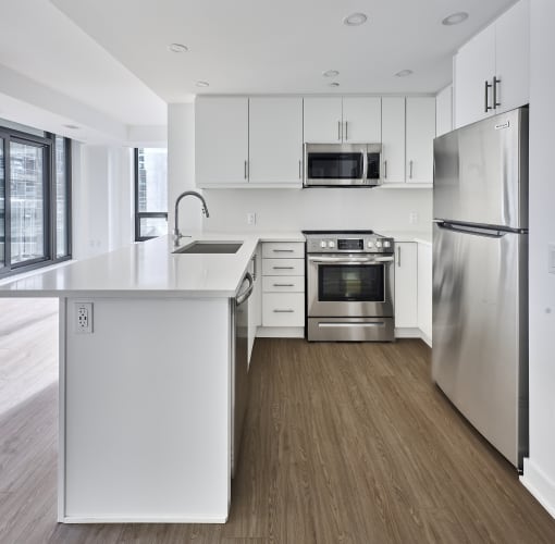 an empty kitchen with white cabinets and stainless steel appliances