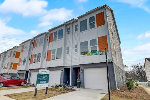 A multi-story apartment building with a sign in front that reads "Monarch Creek".