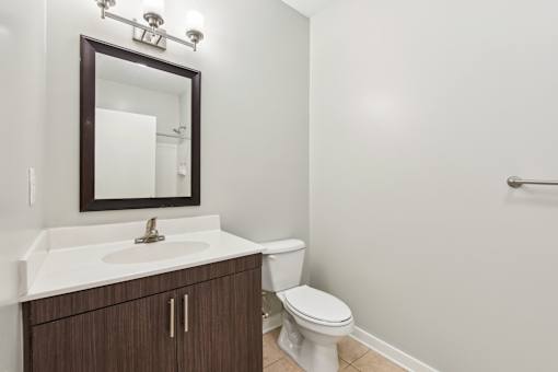 A white sink with a brown cabinet and a white toilet in a bathroom.
