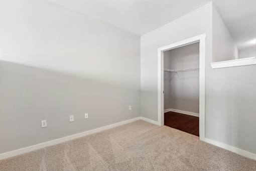 A room with a carpeted floor and a door leading to another room.