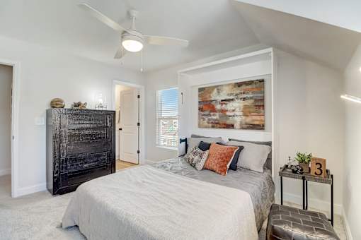 A bedroom with a large bed, a dresser, and a painting on the wall.