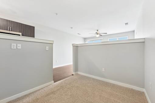 A room with a carpeted floor and a ceiling fan.