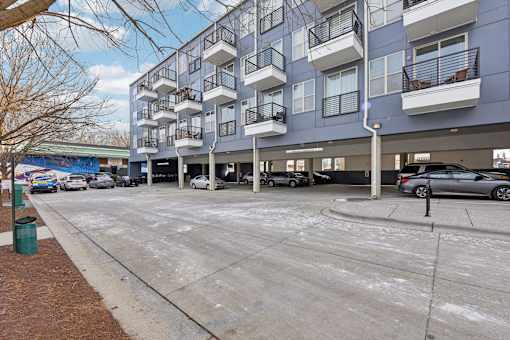 A parking lot in front of a multi-story apartment building.