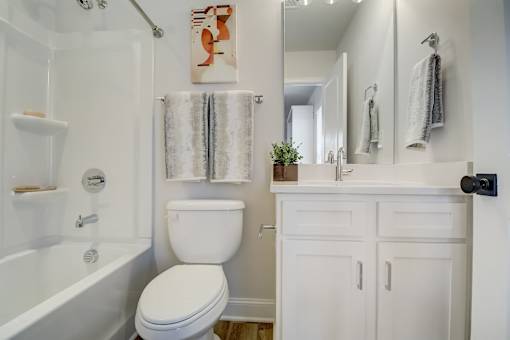 A white toilet sits in a bathroom next to a white bathtub.