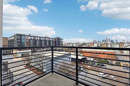 A balcony overlooks a parking lot and buildings.