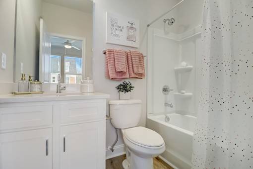 A white bathroom with a toilet, sink, and shower.